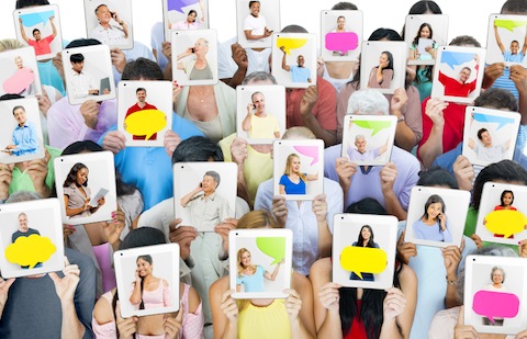 multi ethnic group of people holding tablets in front of the faces