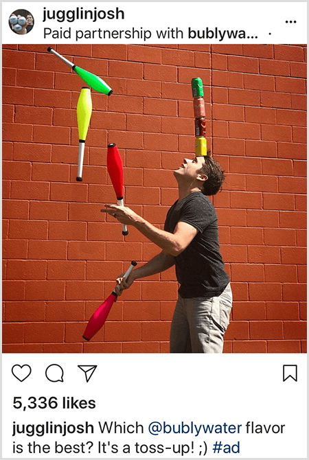 Josh Horton juggles clubs that match the colors of four Bubly water cans stacked on his head. The background is a red brick wall. The photo is an ad Josh created for Bubly water and posted in his Instagram feed with the description Which Bubly Water Flavor Is The Best? It's A Toss Up!