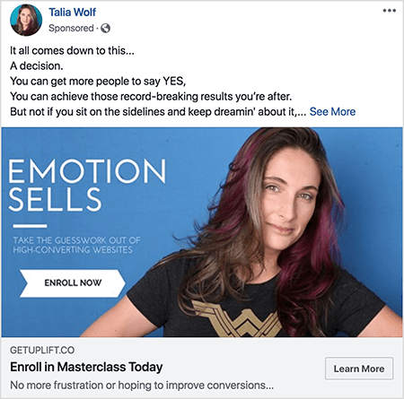 This is a screenshot of a Facebook ad for a masterclass from Talia Wolf. In the ad text, each sentence is on a separate line. It says “It all comes down to this . . . A decision. You can get more people to say YES. You can achieve those record-breaking results you’re after. But not if you sit on the sidelines and keep dreamin’ about it . . . “ After this text is a See More link. The ad image has a blue background with white text and a picture of Talia from the chest up. She is a white woman with brown and purple hair that falls below her shoulders. She’s wearing a black t-shirt with a gold Wonder Woman logo. The text to the left of her photo says “Emotion Sells” and “Take the guesswork out of high-converting websites”. Below this text is a white arrow with black text that says “Enroll Now”. Below the image is the following headline and text: “Getuplift.co” and “Enroll in Masterclass Today” and “No more frustration or hoping to improve conversions”. A Learn More button appears in the lower right.