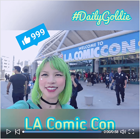 This is a screenshot of a Goldie Chan LinkedIn video with a starter screen. The video was shot horizontally on a smartphone and turned into a square video with blurred letterboxing above and below the video. The starting video image shows Goldie in front of the convention center for LA Comic Con. Goldie appears from the shoulders up. She’s an Asian woman with green hair. She’s wearing makeup, a black choker necklace, and a turquoise shirt. In the letterbox area above the video, #DailyGoldie appears in a light green script font with a turquoise outline. A LinkedIn Like icon with the number 999 appears in a blue box over Goldie’s head. In the letterbox area below the video, the text “LA Comic Con” appears in a light green san serif font with a turquoise outline.