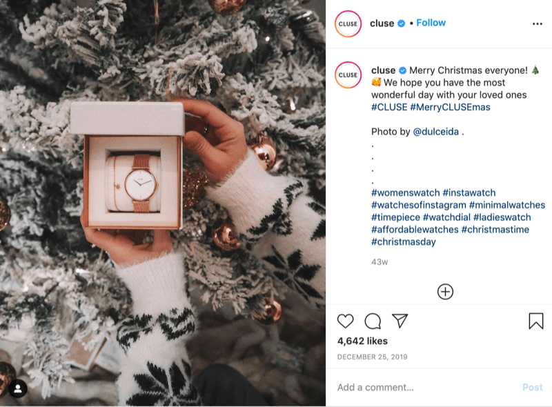 instagram post from @cluse showing a picture of a snowflake-sweatered model holding a watch in front of a snowy tree by @dulceida with the hashtags #cluse and #merryclusemas